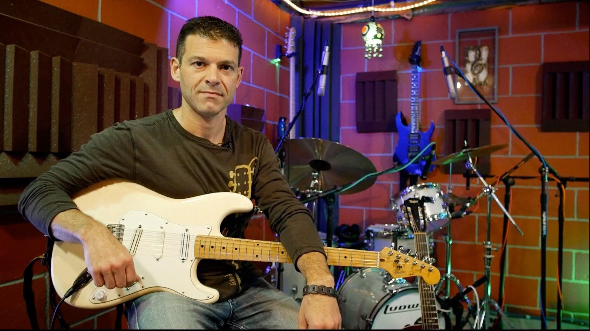 Mike Deiure sitting with his Stratocaster in his recording studio